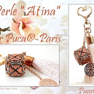 May include: A gold-tone keyring with a pink tassel and a beaded cube charm. The charm is made with brown and gold beads and has a heart design. The keyring also features a gold heart-shaped charm and a round, openwork charm. The text "Perle "Atima" par Puca® - Paris" is visible in the image.