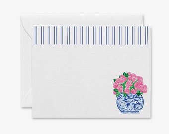 Pode incluir: Um cartão branco com uma borda listrada azul e branca. O cartão apresenta uma ilustração em aquarela de um vaso de porcelana azul e branco com flores cor-de-rosa.
