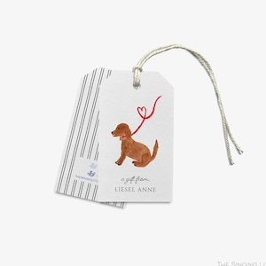May include: A white gift tag with a brown dog illustration and a red heart-shaped leash. The text "a gift from... Liesel Anne" is printed on the tag.