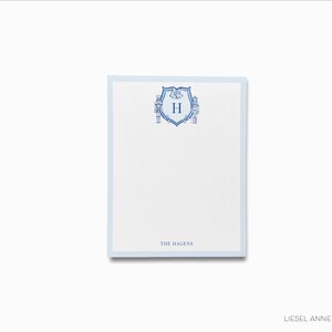 May include: Blue and white personalized notepad with a crest featuring the letter "H" and the text "The Hagens".
