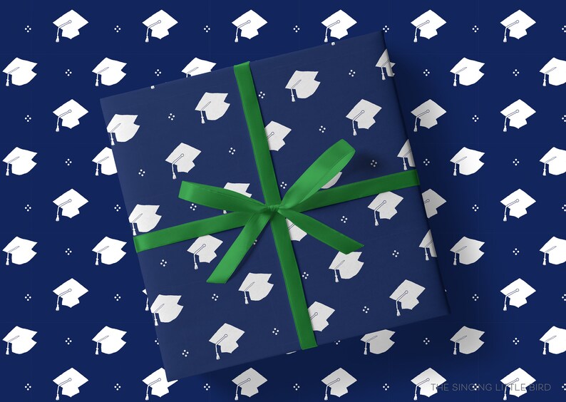 May include: A navy blue gift box with a green ribbon. The box is wrapped in wrapping paper with a white graduation cap pattern.