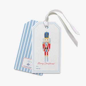 A white gift tag with a blue stripe and a nutcracker illustration on it.