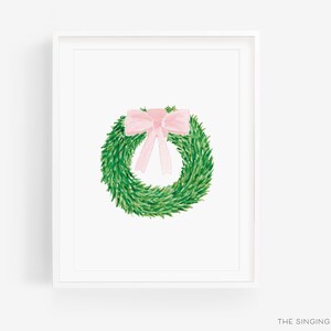 May include: A green wreath with a pink bow on top. The wreath is in a white frame.