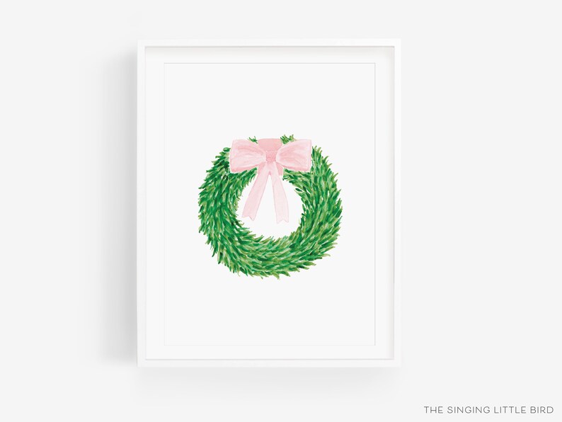 May include: A green wreath with a pink bow on top. The wreath is in a white frame.