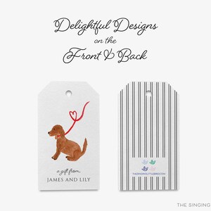 May include: A gift tag with a watercolor illustration of a brown dog on a red leash with a heart at the end. The text on the tag reads "a gift from. JAMES AND LILY". The back of the tag has black and white stripes and the text "THE SINGING LITTLE BIRD.COM".
