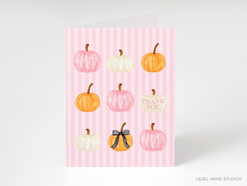 A pink striped card with nine pumpkins of various sizes and colors, including white, orange, and yellow, arranged in a 3x3 grid.