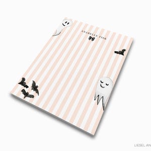 a notebook cover with a striped background and illustrations of bats and a smiling ghost.
