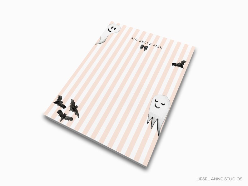 a notebook cover with a striped background and illustrations of bats and a smiling ghost.