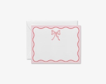 May include: Pink note card with a red scalloped border and a pink bow in the centre.