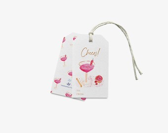 Può includere: Due etichette regalo rettangolari bianche con un cordino, caratterizzate da un'illustrazione ad acquerello di un cocktail rosa in un bicchiere, una fetta di pompelmo e il testo Cheers! con linee per To e From. Motivo a cocktail ripetuto.