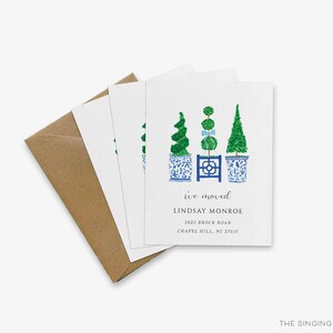 a set of greeting cards with a design of three topiary trees in blue and white pots, along with text indicating that the cards are for "ive moved" and are addressed to "Linda Monroe".