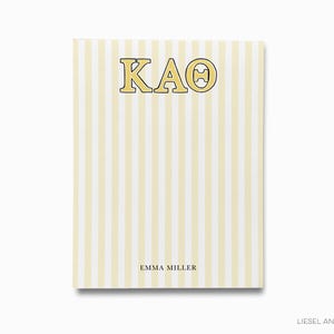 May include: A notepad with a vertical striped pattern in pale yellow and white. The letters "KAO" in a yellow font with a black outline are at the top. The name "EMMA MILLER" is printed at the bottom.