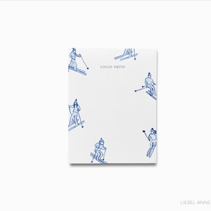 May include: White stationery with blue illustrations of skiers on a white background. The text "LOGAN SMITH" is printed in the centre of the page.