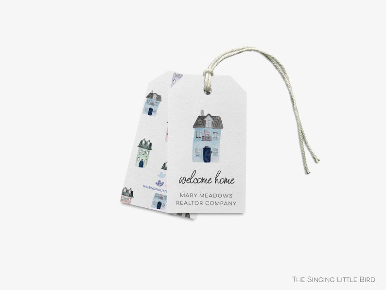 Puede incluir: Una etiqueta de regalo blanca con una ilustraci&oacute;n de una casa azul y el texto "welcome home"  "Mary Meadows Realtor Company" y un peque&ntilde;o logotipo que dice "The Singing Little Bird".