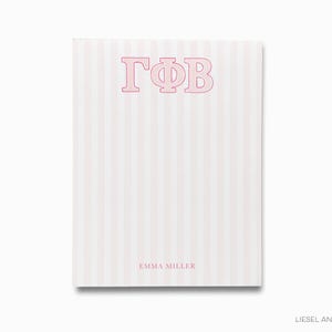 May include: A notepad with a vertical pink and white striped pattern. The top of the notepad features the Greek letters ΓΦB in pink. The name "EMMA MILLER" is printed in pink at the bottom.