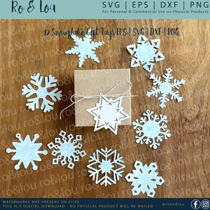 May include: A collection of twelve white snowflake gift tags, in various designs, arranged around a small brown gift box tied with twine. The image includes text that reads "12 Snowflake Gift Tags EPS | SVG | DXF | PNG".