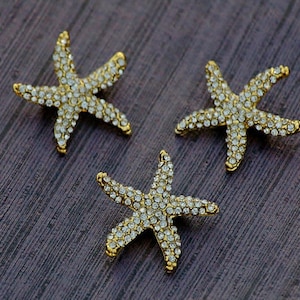 May include: Three gold starfish ornaments covered in clear rhinestones.
