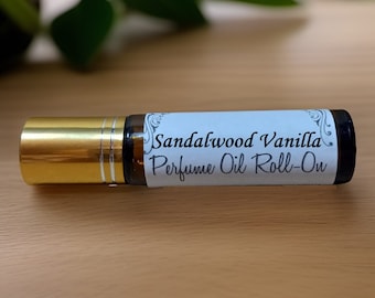 May include: A gold and brown glass roll-on bottle with a white label that reads "Sandalwood Vanilla Perfume Oil Roll-On".