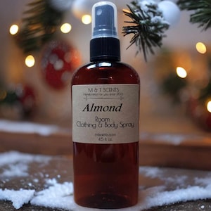 May include: A brown glass bottle with a black spray nozzle and a brown label that reads "M&T SCENTS Handcrafted for you since 2013 Almond Room Clothing & Body Spray mtscents.com 4.5 fl oz."