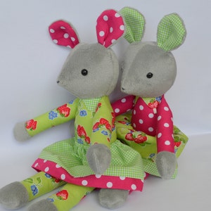 May include: Two grey plush mice wearing dresses. One mouse is wearing a green dress with pink polka dots and white flowers. The other mouse is wearing a pink dress with white polka dots and red strawberries.