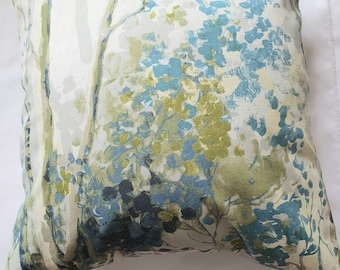 May include: A decorative cushion with a floral pattern in shades of blue, green, and white. The cushion features a watercolour-like design of abstract flowers and branches.