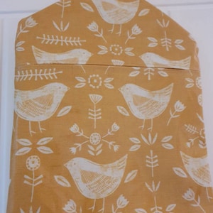 Könnte beinhalten: Eine gelbe Stoffaufbewahrungstasche mit einem weißen Vogel- und Blumenmuster. Die Tasche hat einen Kordelverschluss und eine Aufhängeschlaufe.
