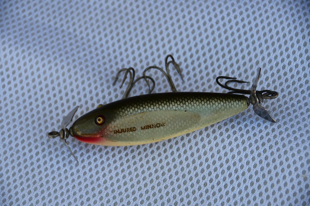Seven Creek Chub wood injured minnow fishing lures, together with a plastic example, a plunker and a sold at auction on 21st June