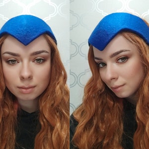 May include: A vibrant blue headband with a V-shaped front. The headwear is made of a felt-like material. The image shows the headband from multiple angles, showcasing its design and shape. This accessory is a stylish addition to any outfit.