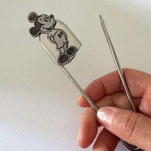 Pu&ograve; includere: Segnalibro color argento con un'illustrazione dettagliata di Topolino. Il segnalibro &egrave; tenuto in mano, mostrando la silhouette del personaggio. Il segnalibro &egrave; realizzato in metallo sottile e resistente. Un accessorio utile.