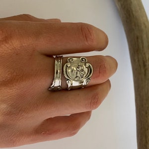May include: Two silver rings. One ring features a Mickey Mouse design, while the other has a simple, elegant shape. The rings are made of a shiny, metallic material and are worn on a finger.
