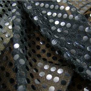 以下が含まれることがあります： 黒の透き通った生地に、銀色のスパンコールが水玉模様に散りばめられています。