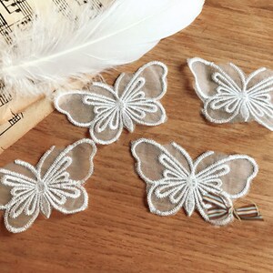 May include: Four white lace butterfly appliques with delicate embroidery details. The appliques are perfect for adding a touch of elegance to clothing, crafts, or home decor.