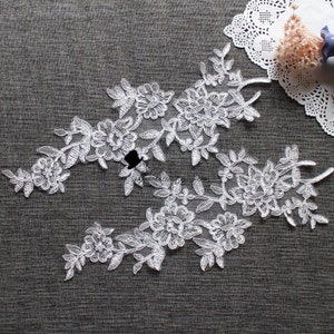 May include: White lace trim with a floral design. The lace is delicate and intricate, with small flowers and leaves.