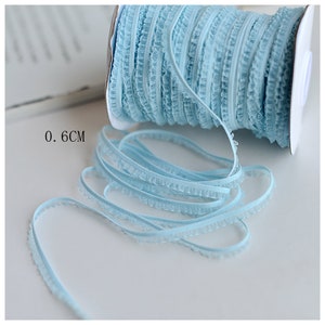 May include: A spool of light blue ruffled trim with a 0.6 cm width. The trim is made of a soft, delicate fabric and is perfect for adding a touch of elegance to any project.