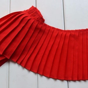 May include: Red pleated fabric trim with a scalloped edge. This trim is perfect for adding a touch of elegance to any project.