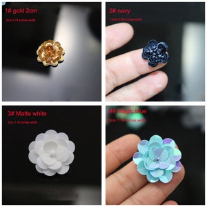 May include: Four flower-shaped embellishments: a 2cm gold sequin flower, a 1.5cm navy blue flower, a 3cm matte white flower, and a 3cm iridescent magic blue flower. Each item is labeled with its color and width in inches and centimeters.