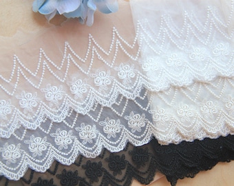 Peut inclure: Garniture en dentelle blanche avec un bord festonné et des accents de perles. La garniture est superposée à une garniture en dentelle noire.