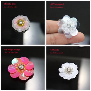 May include: A collection of four flower-shaped sequin patches, each measuring 1.18 inches in width. The set includes a matte pink flower, a transparent flower, a magic orange flower, and a white flower, all featuring a central rhinestone.