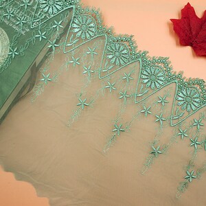 May include: Green lace trim with a scalloped edge and floral embroidery. The lace has a delicate, airy feel and would be perfect for adding a touch of elegance to any project.