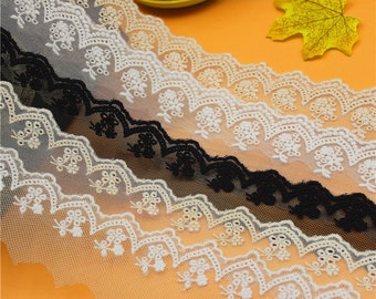 Peut inclure: Quatre couleurs différentes de dentelle blanche délicate avec un bord festonné et un motif floral. La dentelle est présentée sur une surface orange clair.