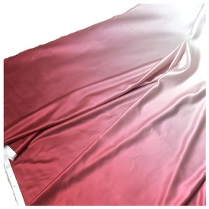 May include: A gradient fabric with a smooth, silky texture. The fabric transitions from a deep red to a light pink.