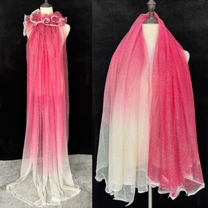 K&ouml;nnte beinhalten: Ein rosa-wei&szlig;er Ombre-T&uuml;llstoff mit Glitzer. Der Stoff ist &uuml;ber eine Schaufensterpuppe drapiert und hat einen R&uuml;schenkragen.