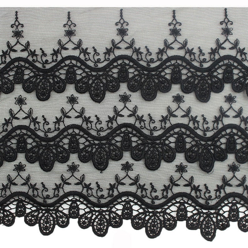 May include: Black lace trim with a scalloped edge and floral embroidery. The lace has a delicate, intricate design.