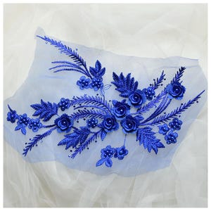 May include: Blue floral applique with pearl accents. This delicate embroidery features 3D flowers and leaves, perfect for adding a touch of elegance to clothing or crafts.