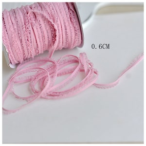 May include: Pink ruffled elastic trim, 0.6 inches wide. This trim is perfect for adding a touch of elegance to any project.