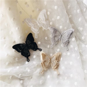 May include: Four embroidered butterfly appliques in different colors and styles. The butterflies are black, white, gray, and beige.