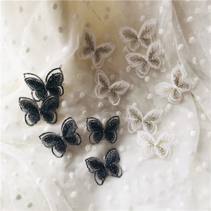 Peut inclure: Assortiment d'appliques de papillon brodées en noir et blanc. Les papillons sont délicats et complexes, avec des ailes et des antennes détaillées.