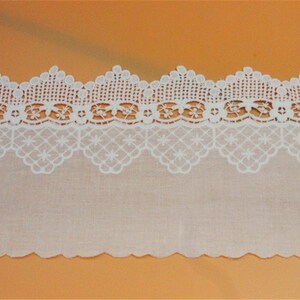 May include: White cotton lace trim with a scalloped edge and a delicate floral pattern. The lace is approximately 1 inch wide.