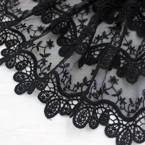 May include: Black lace trim with a delicate floral pattern. The lace is made of a fine mesh fabric and has a scalloped edge.