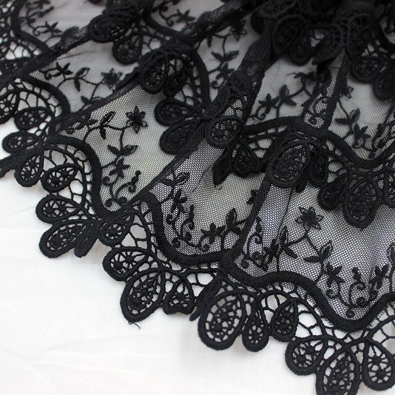 May include: Black lace trim with a delicate floral pattern. The lace is made of a fine mesh fabric and has a scalloped edge.